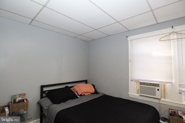 bedroom featuring a drop ceiling, multiple windows, and cooling unit