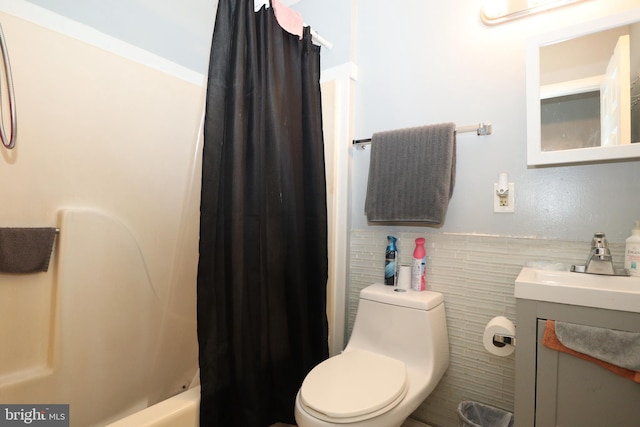 full bathroom with vanity, tile walls, shower / bath combo with shower curtain, and toilet