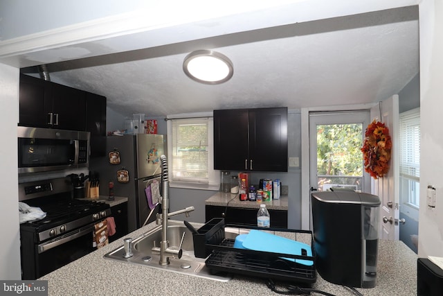 kitchen featuring a textured ceiling, stainless steel appliances, sink, and vaulted ceiling