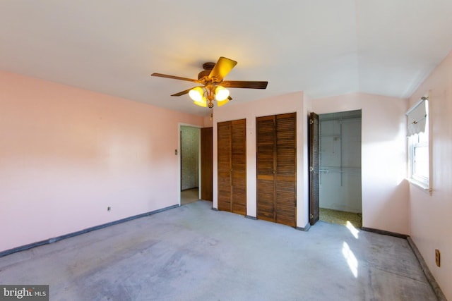 unfurnished bedroom featuring multiple closets, light colored carpet, and ceiling fan