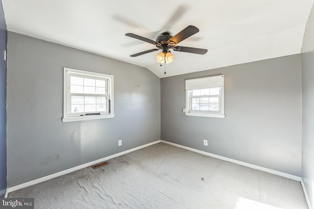 carpeted spare room with a wealth of natural light, lofted ceiling, and ceiling fan