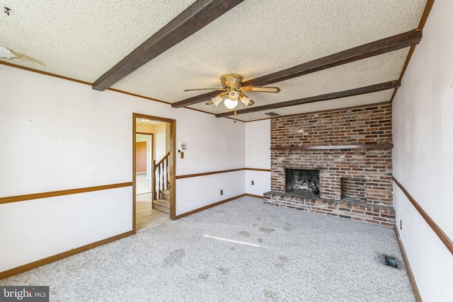 unfurnished living room with beam ceiling, light carpet, a brick fireplace, a textured ceiling, and ceiling fan