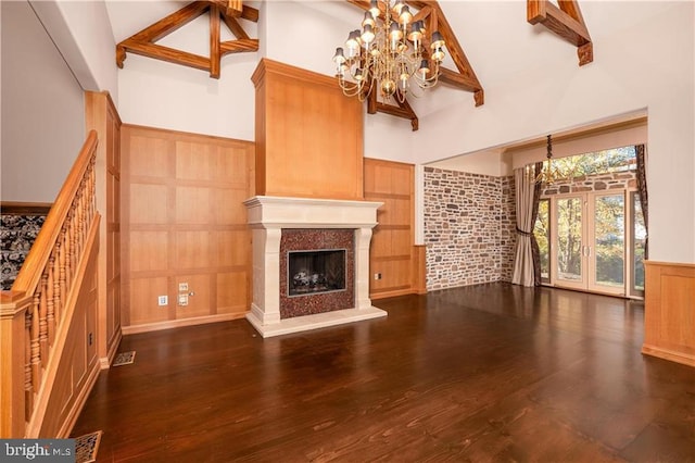 unfurnished living room with french doors, dark wood-type flooring, beam ceiling, high vaulted ceiling, and an inviting chandelier