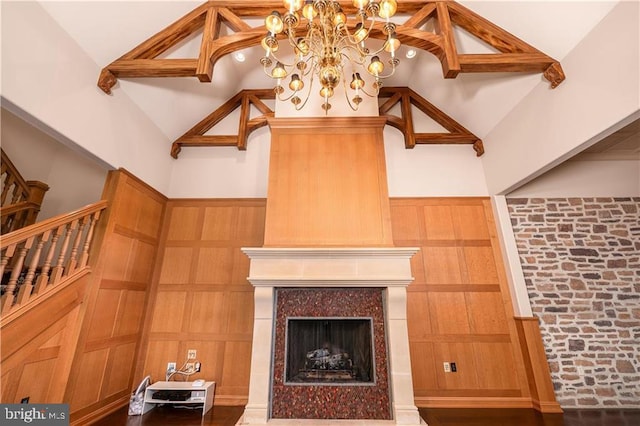 living room with a notable chandelier, wooden walls, high vaulted ceiling, and a fireplace