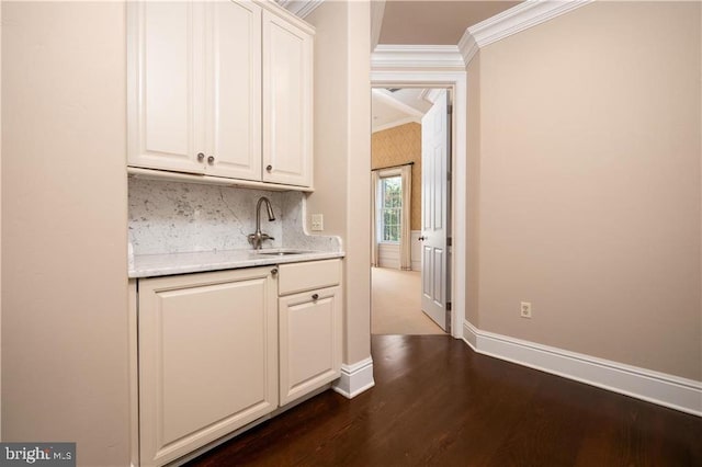 bar featuring decorative backsplash, ornamental molding, sink, white cabinetry, and dark hardwood / wood-style flooring