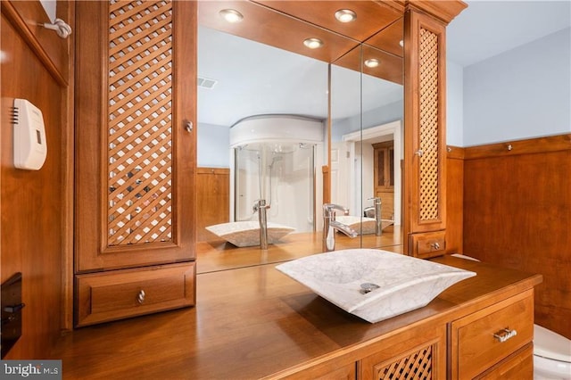 bathroom with vanity, toilet, wooden walls, and an enclosed shower