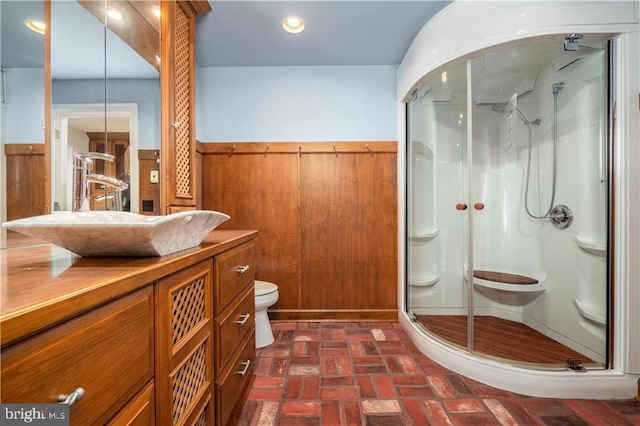 bathroom featuring wood walls, vanity, toilet, and an enclosed shower