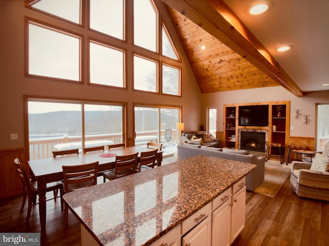 kitchen featuring beam ceiling, a kitchen island, light stone counters, a mountain view, and white cabinets