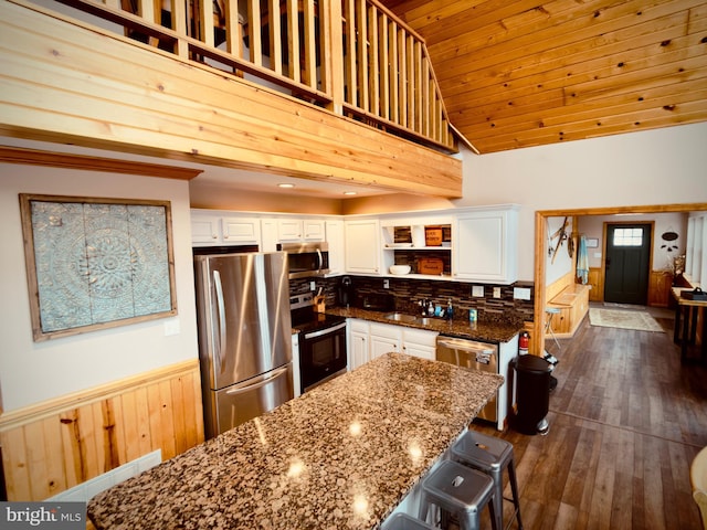 kitchen featuring white cabinetry, wooden ceiling, stainless steel appliances, dark stone countertops, and a kitchen island