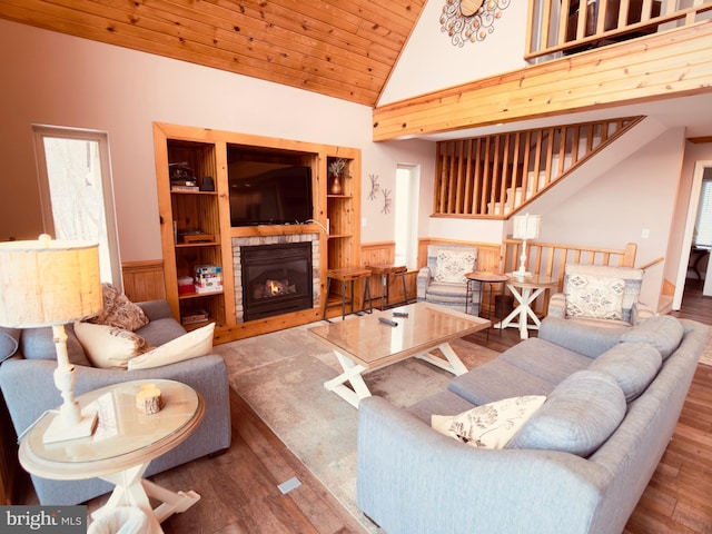 living room featuring wood-type flooring, wooden ceiling, high vaulted ceiling, and a stone fireplace