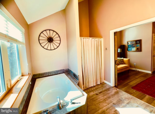 bathroom featuring a bath, hardwood / wood-style floors, and vaulted ceiling