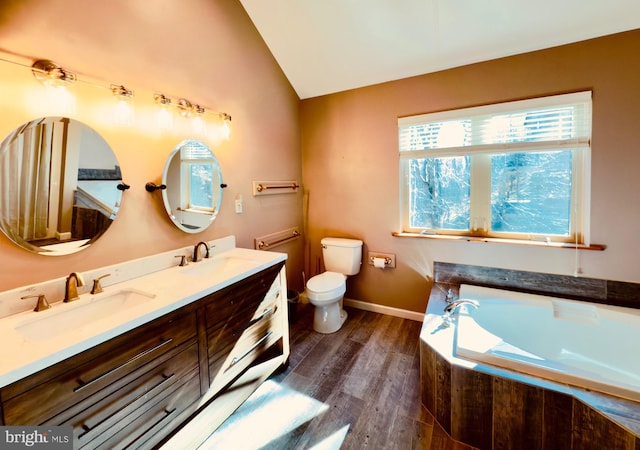 bathroom with vanity, lofted ceiling, hardwood / wood-style flooring, toilet, and tiled tub