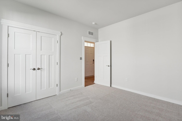 unfurnished bedroom featuring light carpet and a closet