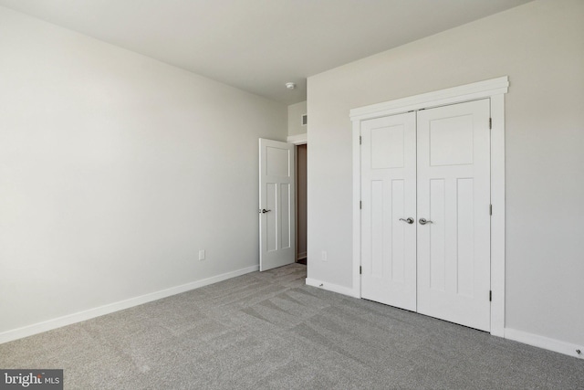 unfurnished bedroom featuring light carpet and a closet