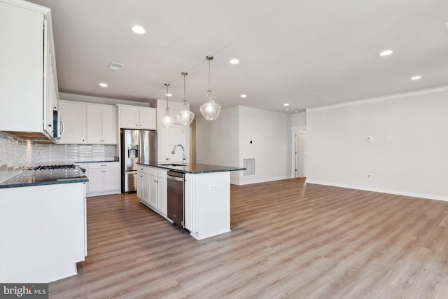 kitchen featuring an island with sink, sink, white cabinets, light wood-type flooring, and appliances with stainless steel finishes