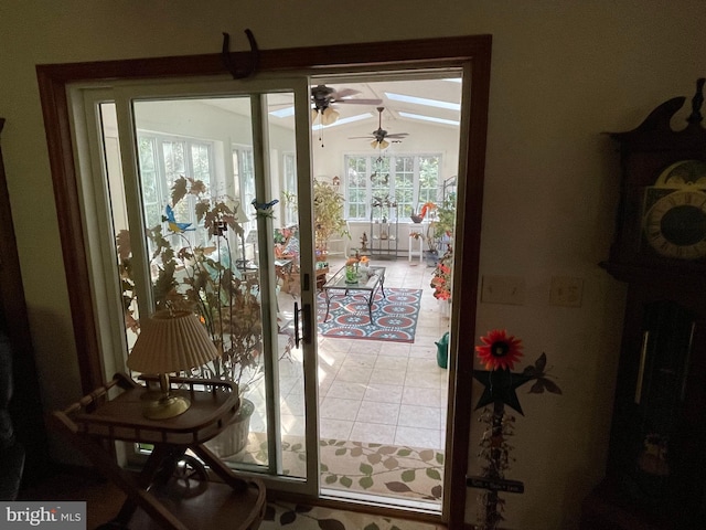 doorway featuring ceiling fan, light tile patterned floors, and vaulted ceiling