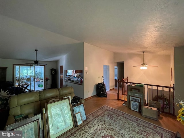 living room with light hardwood / wood-style floors, a textured ceiling, lofted ceiling, and ceiling fan