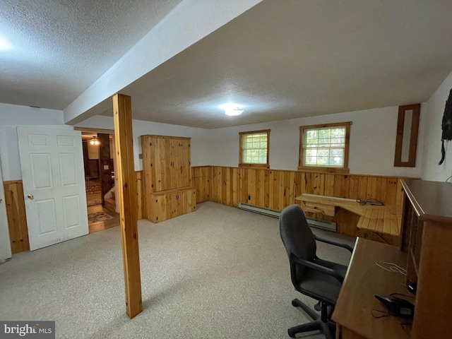 carpeted office space with baseboard heating, wooden walls, and a textured ceiling