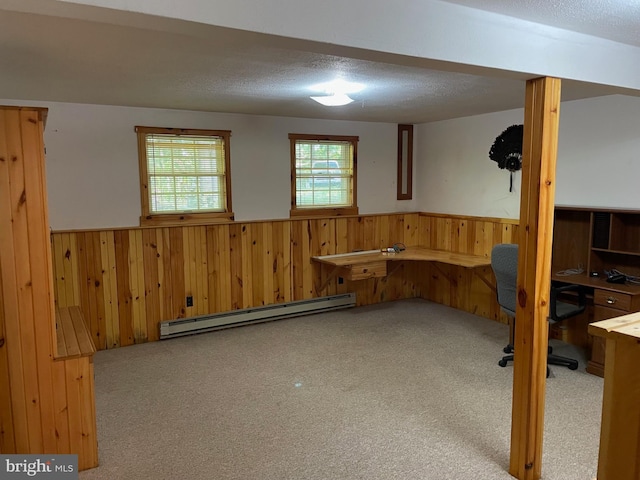 basement featuring wood walls, a baseboard heating unit, a textured ceiling, and carpet