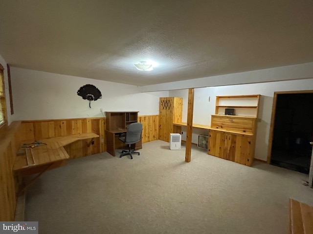 carpeted office with a textured ceiling and wood walls