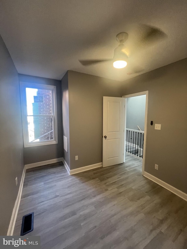 spare room with a textured ceiling, wood-type flooring, and ceiling fan