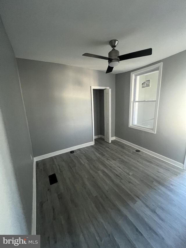 unfurnished bedroom with a closet, dark hardwood / wood-style floors, and ceiling fan