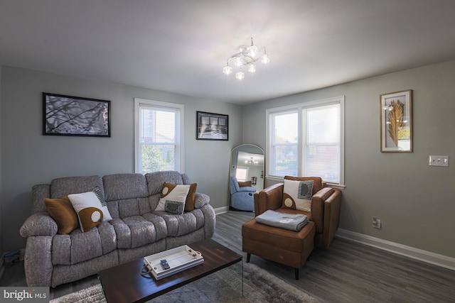 living room with dark wood-type flooring, a healthy amount of sunlight, and a notable chandelier