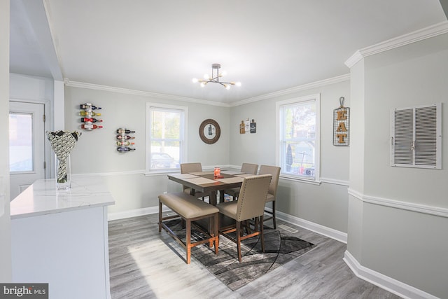 dining space featuring wood-type flooring, an inviting chandelier, and crown molding