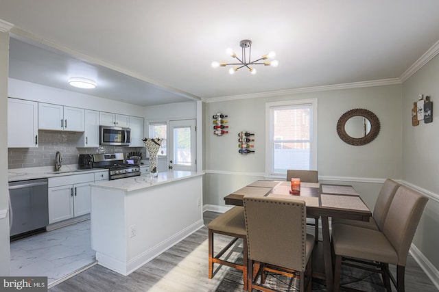 kitchen featuring a wealth of natural light, white cabinetry, appliances with stainless steel finishes, and decorative light fixtures