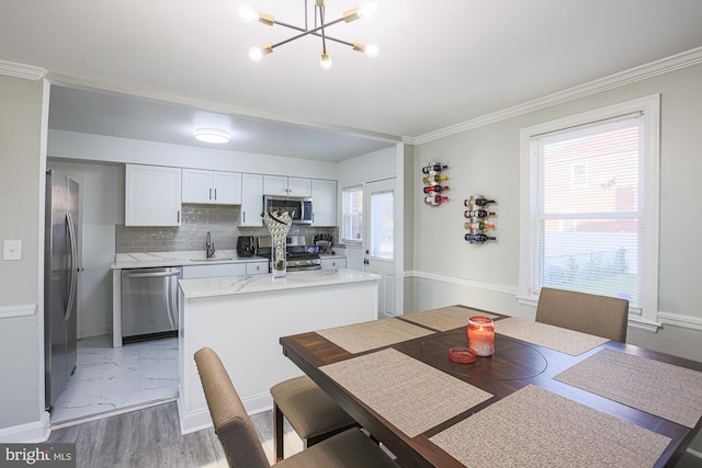 dining space featuring sink, an inviting chandelier, hardwood / wood-style floors, and crown molding