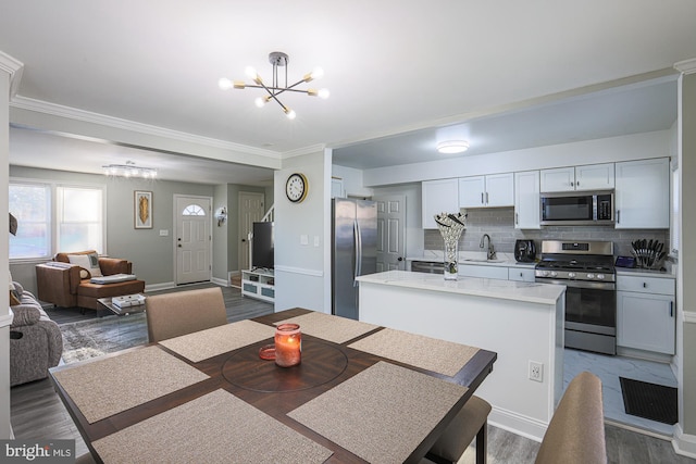 dining space featuring ornamental molding, dark wood-type flooring, sink, and a notable chandelier