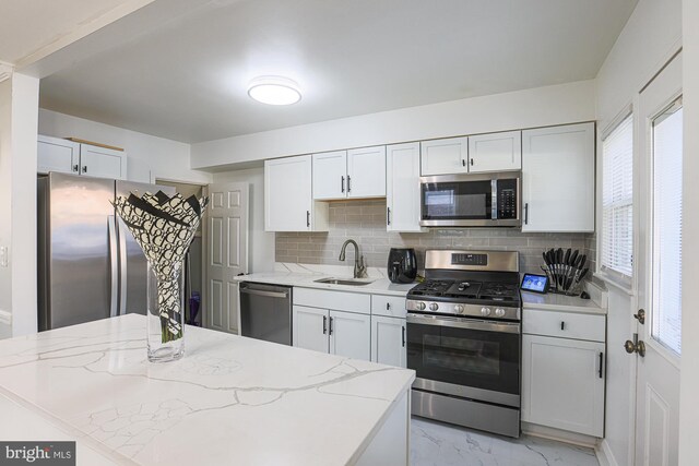 kitchen with a wealth of natural light, stainless steel appliances, sink, and decorative backsplash