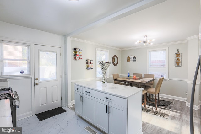 kitchen with ornamental molding, stainless steel range, a chandelier, and light stone counters