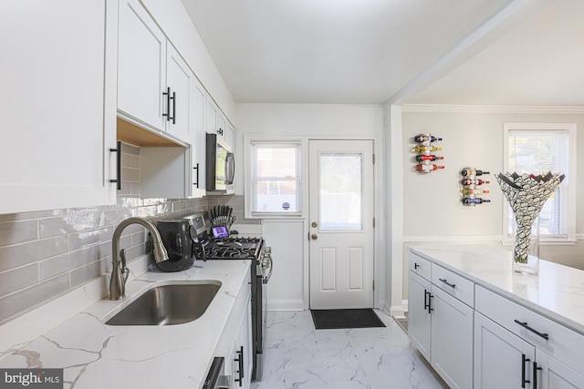 kitchen with sink, light stone counters, appliances with stainless steel finishes, backsplash, and white cabinets