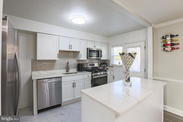 kitchen with light stone counters, a kitchen island, appliances with stainless steel finishes, sink, and white cabinets