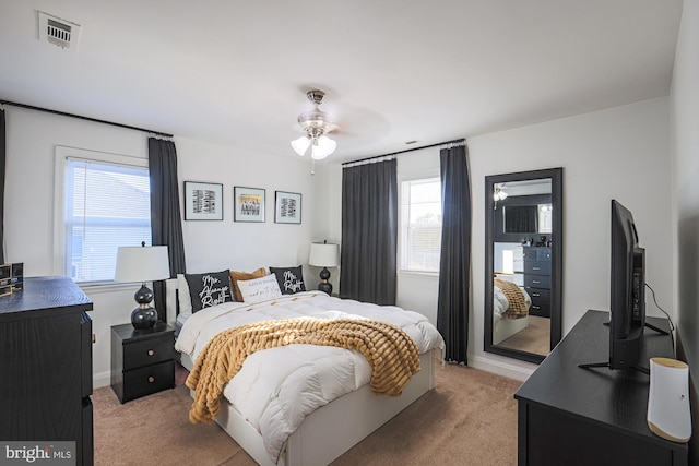 bedroom featuring ceiling fan, multiple windows, and light carpet