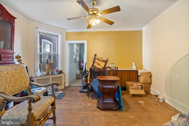 sitting room with a textured ceiling, ceiling fan, wood-type flooring, and crown molding