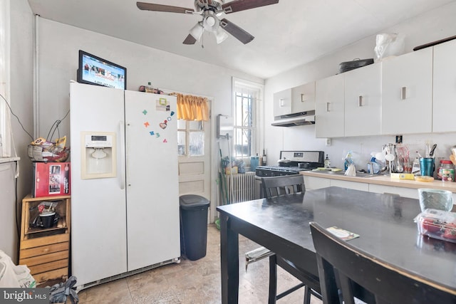 kitchen featuring black gas range oven, ceiling fan, white cabinetry, white fridge with ice dispenser, and range hood