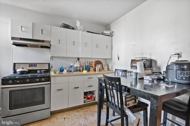 kitchen featuring gas stove, white cabinetry, and sink