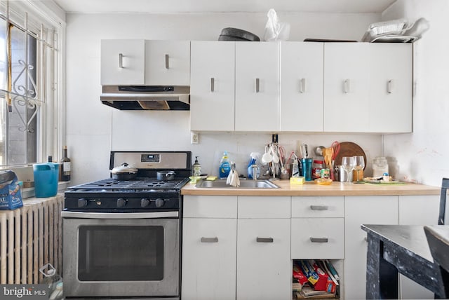 kitchen featuring gas range, white cabinetry, radiator heating unit, and sink