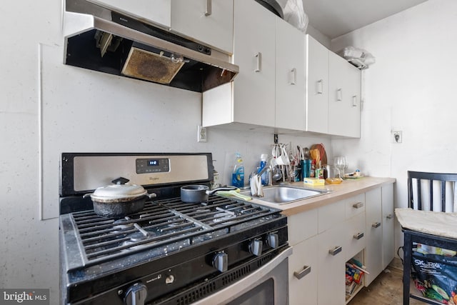 kitchen featuring white cabinets, gas stove, and sink