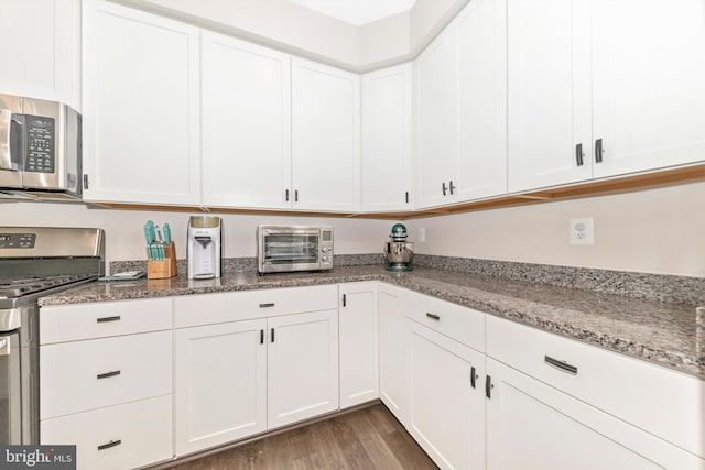 kitchen featuring stone counters, dark wood-type flooring, appliances with stainless steel finishes, and white cabinets