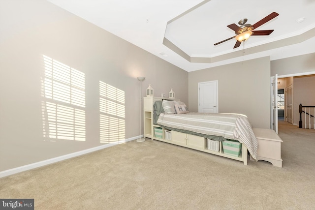 carpeted bedroom featuring multiple windows, crown molding, a raised ceiling, and ceiling fan