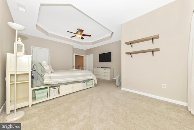 bedroom featuring light carpet, a tray ceiling, and ceiling fan