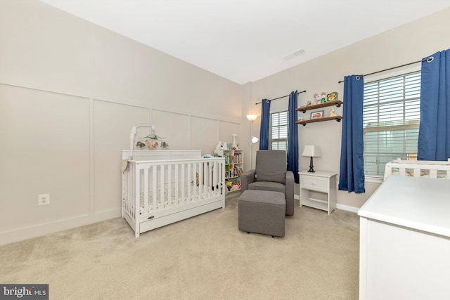 bedroom featuring lofted ceiling, light colored carpet, and a crib