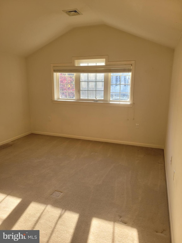 carpeted empty room with lofted ceiling