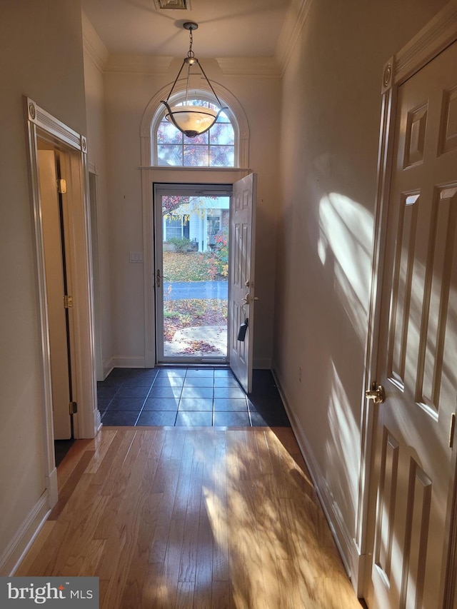 entryway with ornamental molding and dark hardwood / wood-style floors