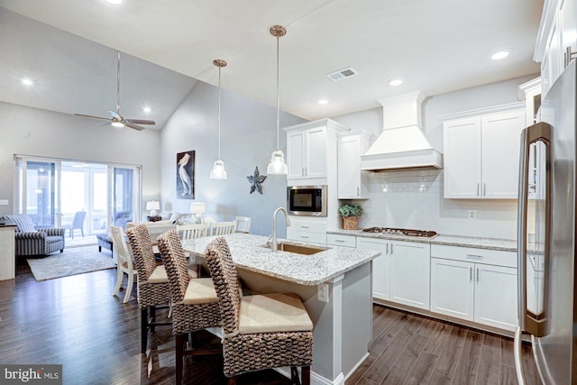 kitchen featuring dark hardwood / wood-style floors, custom range hood, sink, light stone countertops, and pendant lighting