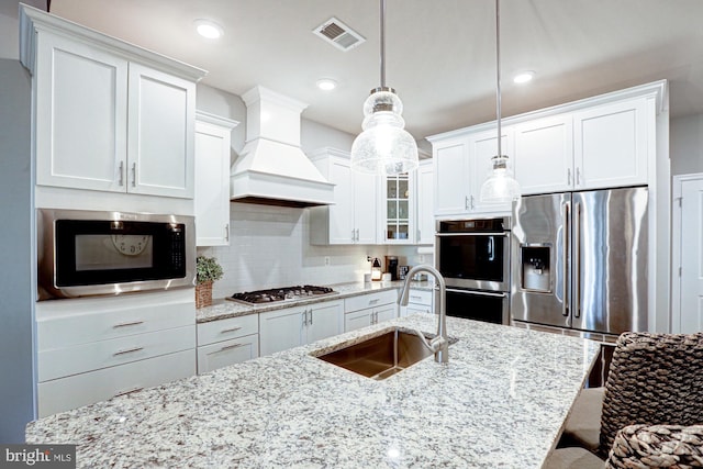 kitchen featuring hanging light fixtures, stainless steel appliances, sink, custom exhaust hood, and white cabinets