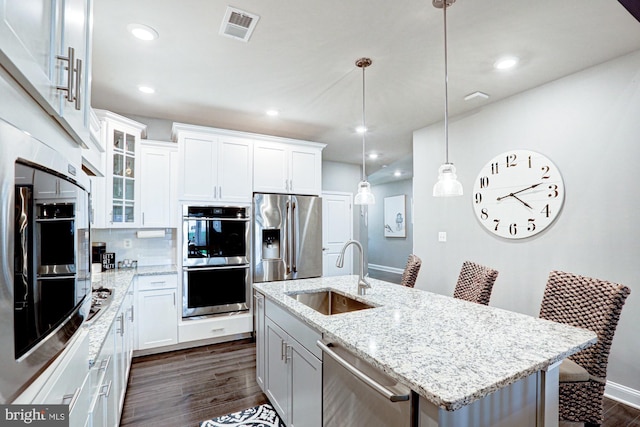 kitchen with white cabinets, an island with sink, dark hardwood / wood-style floors, sink, and stainless steel appliances